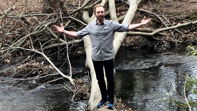 Gideon Banner standing on a log across a river used for National Grid's green collar jobs story